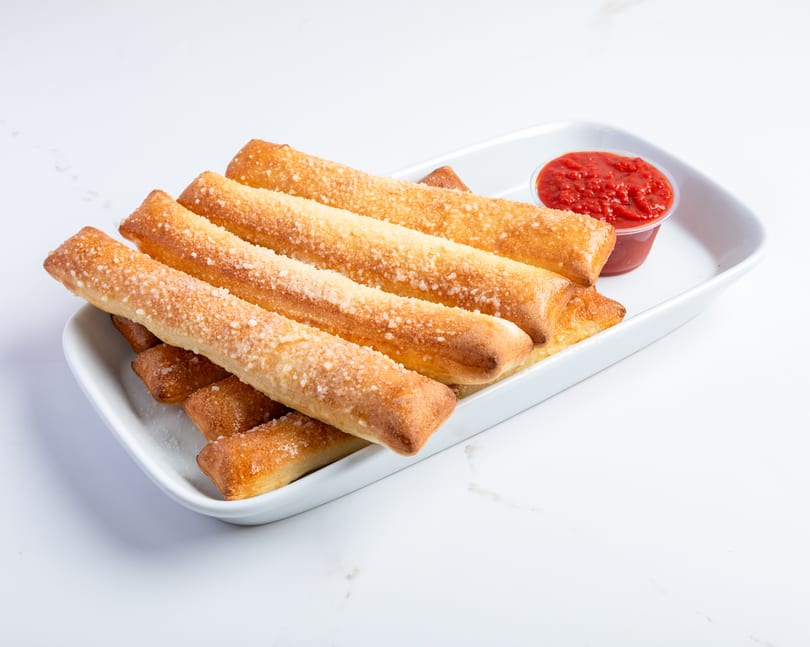 Golden-brown breadsticks, sprinkled with Parmesan cheese, served with a side of marinara sauce.