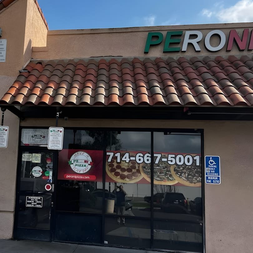 Peroni Pizza restaurant exterior with a tiled awning, large windows, and a prominent sign.